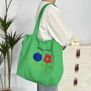 Nahaufnahme der grünen Kordelzug-Tasche mit Tulpen-Stickerei auf Nylonstoff