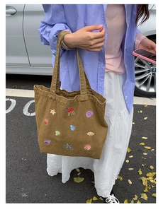 Close-up of canvas tote bag featuring detailed colorful jellyfish and starfish embroidery