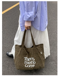 Detail of leopard print tote bag with art lettering and YE YU label held by model