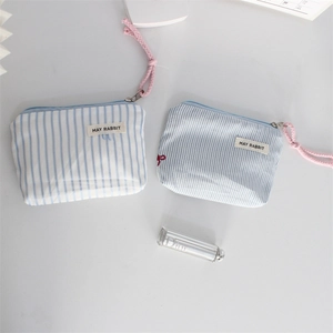 Close-up of blue striped fabric pouches with zippers and pink decorative tassels