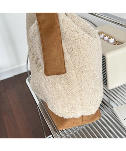 Detailed view of plush off-white lamb wool and brown suede texture on a crossbody bag