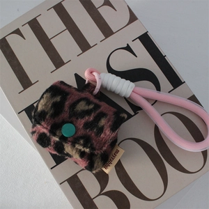 Detail of plush leopard print earphone case with pink woven lanyard on a fashion book