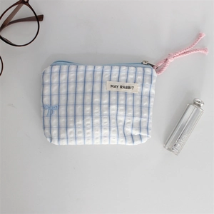 Detail of blue striped cotton cosmetic pouch with pink zipper pull and bow embroidery