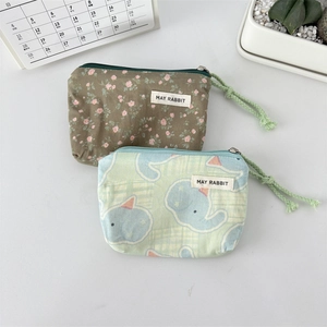 Close-up of canvas pouches with floral and elephant prints and woven zipper pulls