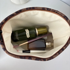Top view of leopard print suede makeup bag showing spacious interior with skincare items