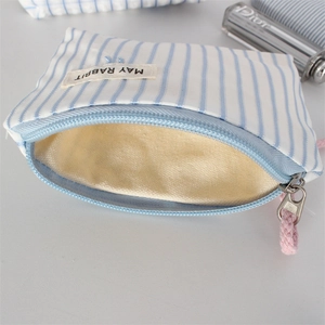 Close-up of blue striped canvas pouch with pink zipper puller and brand tag detail