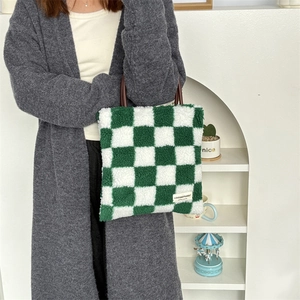 Détail du sac cabas peluche à damier avec anses en cuir marron et étiquette tissée