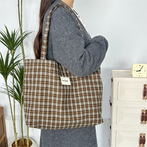 Détail du sac cabas en laine à carreaux classique avec étiquette latérale et bandoulière