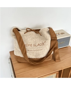 Detail of plush sherpa shoulder bag with brown suede trim and embroidered French text