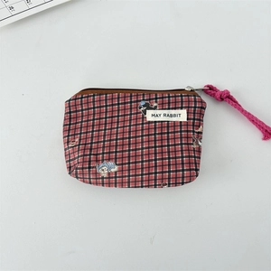Detail of red and black checkered canvas coin purse with zipper and cartoon animal patch