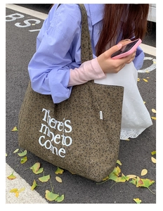 Detail of leopard print canvas tote bag with white handwritten graphic text on street