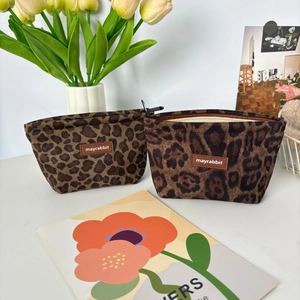 Detail of leopard print suede makeup bags with premium zippers and brand logo patch
