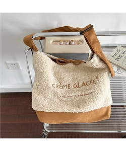 Detail of plush suede crossbody bag featuring French embroidery and adjustable strap