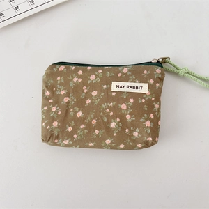 Flat lay of an olive green floral canvas pouch with pink patterns and a zipper closure