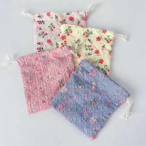 Macro view of four quilted cotton drawstring bags with cute cartoon and floral prints