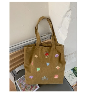 Detail of canvas tote bag featuring colorful ocean embroidery of starfish and jellyfish