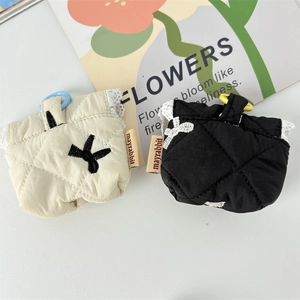 Close-up of quilted floral earphone cases with lace trim and brand tags on white desk