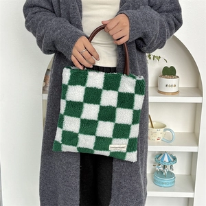 Détail du sac cabas en peluche à damier vert avec anses en cuir et étiquette brodée