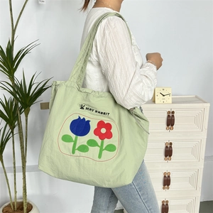 Detail der minzgrünen Einkaufstasche mit Blumenstickerei und May Rabbit Logo