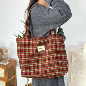 Grand sac cabas classique à carreaux rouges porté à l'épaule dans un décor cosy