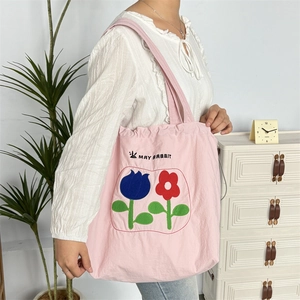 Detail einer rosa Stofftasche mit Kordelzug und einem floralen Tulpenmuster-Design