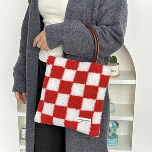Détail du sac cabas en peluche à damier rouge avec étiquette de créateur originale