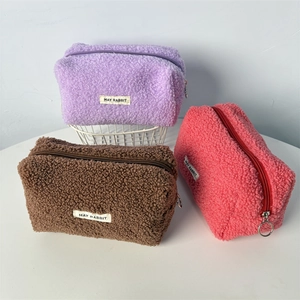 Close-up of three teddy fleece pencil cases in purple, brown, and pink with metal zippers