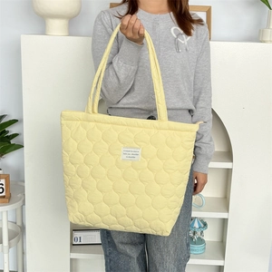Detail der gelben Stepptasche mit kreisförmiger Naht und weißem Textil-Logoaufnäher