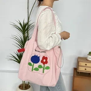 Detail der rosa Canvas-Einkaufstasche mit Blumenstickerei und Kordelzug an der Seite