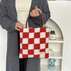 Détail du sac fourre-tout à carreaux rouges et blancs avec anses en cuir et étiquette