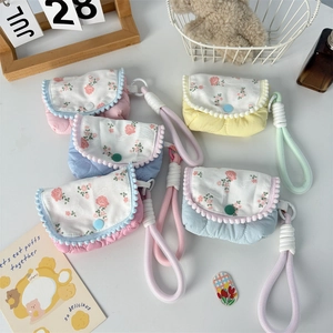 Detailed close-up of quilted floral coin purse with pom-pom trim and woven handle