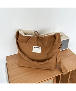 Detail of caramel suede crossbody bag featuring white faux shearling lining and SEEYOU patch