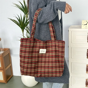 Détail du grand sac cabas en laine à carreaux rouges et verts avec étiquette tissée
