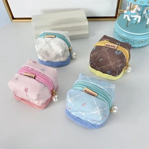 Detail of four floral fabric mini headphone cases with pearl zipper pendants and logo labels