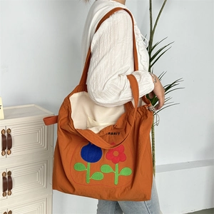 Detail der orangefarbenen Einkaufstasche mit Blumenstickerei und Rabbit-Aufdruck
