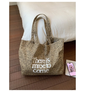 Detail of leopard print canvas tote bag with 'There is more to Come' artistic lettering