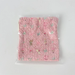 Detail of pink quilted drawstring bag with cartoon bear prints and textured fabric