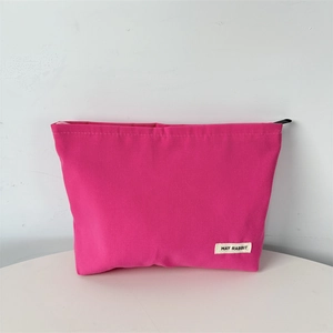 Detailed close-up of a magenta canvas cosmetic bag featuring a MAY RABBIT logo label