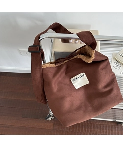 Detail of dark brown faux suede crossbody bag with soft plush lining and woven logo tag