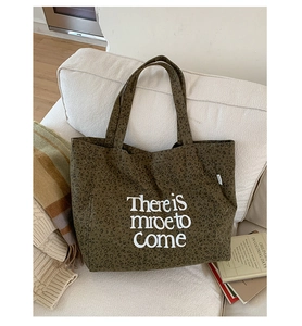 Detail of leopard print canvas tote bag with white letter slogan on fabric surface