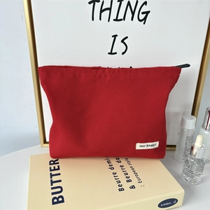 Close-up of red canvas makeup bag with durable zipper and brand tag in lifestyle setting