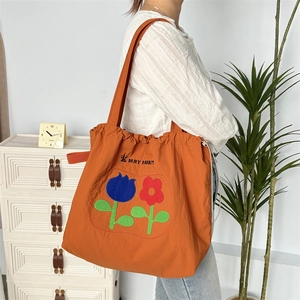 Detailansicht der orangefarbenen Kordeltasche mit Blumenprint und Textilgurten