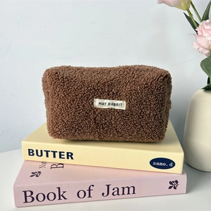 Detailed texture of brown teddy fleece pouch with white May Rabbit label on soft book