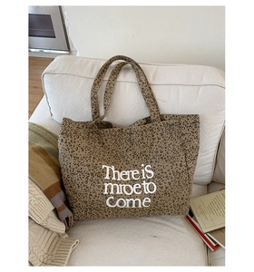 Detail shot of leopard print canvas tote bag with white There is more to Come text