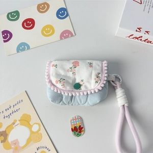 Detailed view of mini floral quilted bag with pink pompom trim and woven hand strap