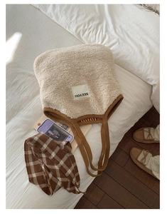 Close-up of cream faux shearling tote bag with SEEYOU label and brown woven handles
