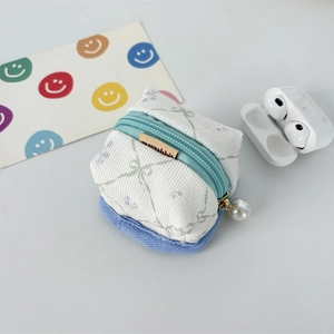 Close-up of floral fabric earbud case with white pearl pendant and brown woven label