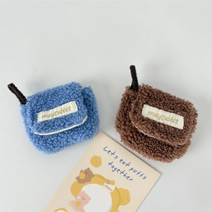 Detail of plush lamb wool earphone pouches in blue and brown with soft woven tags