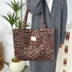 Détail du cabas en peluche léopard rose et noir avec étiquette de marque en tissu