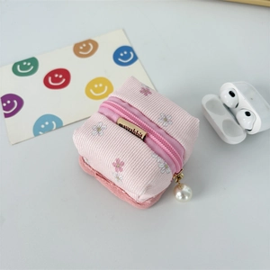 Pink corduroy floral earphone case with a pearl zipper pull and brand tag details
